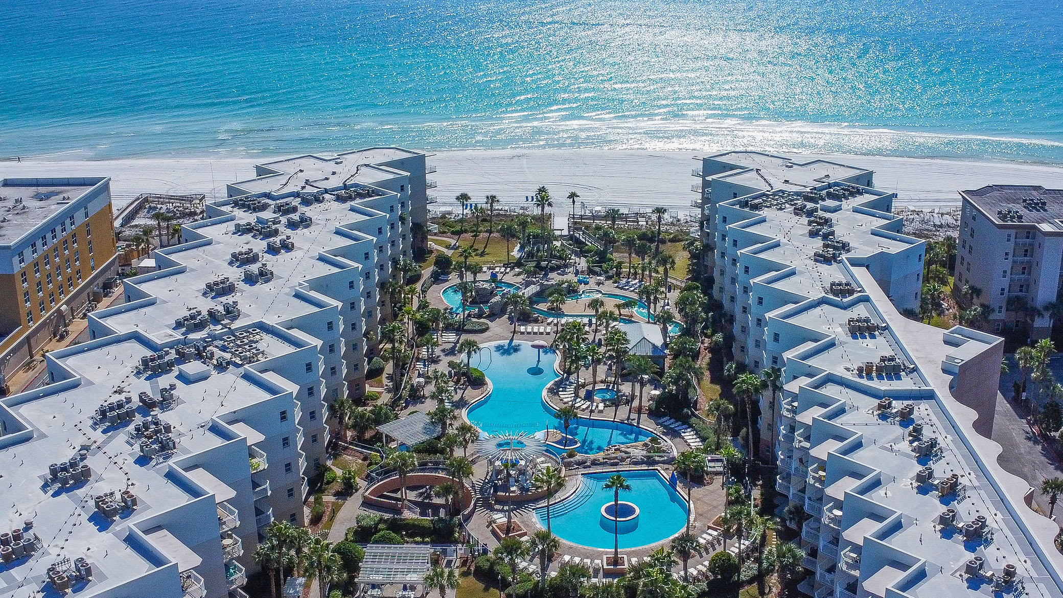 Aerial view of Waterscape Resort on Okaloosa Island, Fort Walton Beach, showing the courtyard pools and the Gulf beach